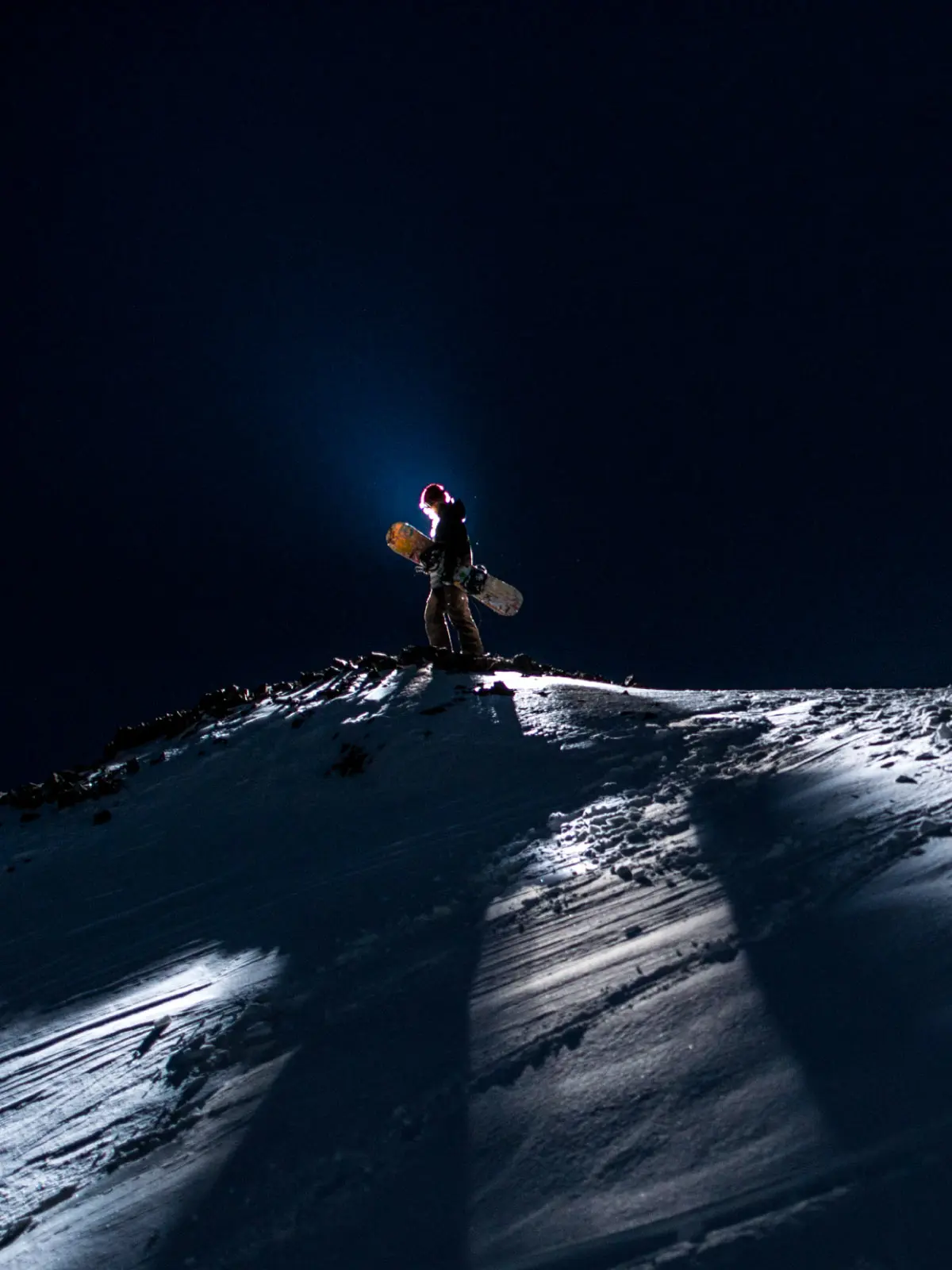 Snowboarder at the top of Boreal Mountain at night
